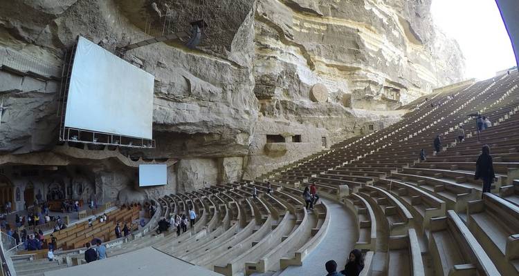 Ruim uit rots gehouwen amfitheater met bezoekers.