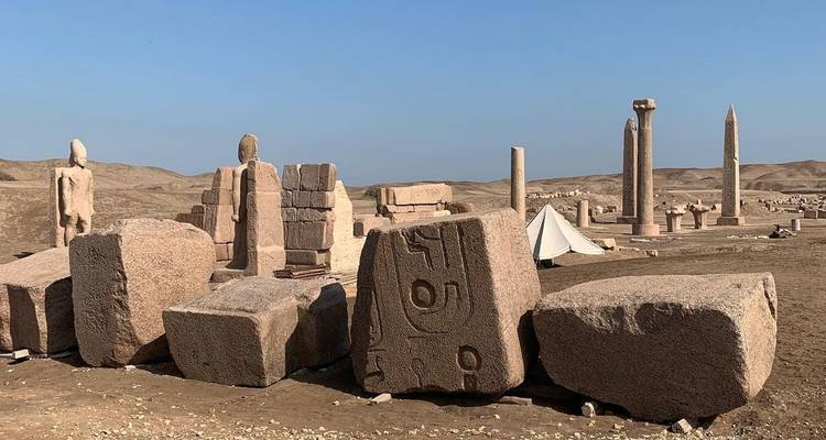 Woestijnruïnes met verstrooide stenen en zuilen.