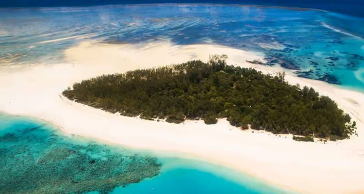 Luftaufnahme einer Insel mit üppigem Grün und türkisfarbenem Wasser.