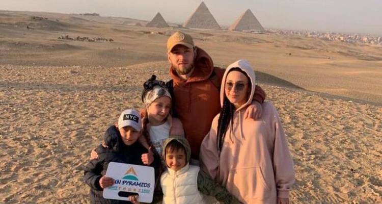 Familie poseert met piramides op de achtergrond.