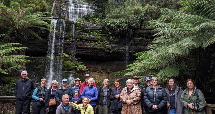 Groupe de personnes posant devant une cascade dans une forêt.
