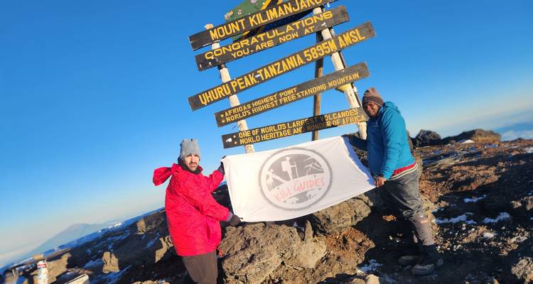 Deux personnes tenant un drapeau au sommet d'Uhuru, mont Kilimandjaro.