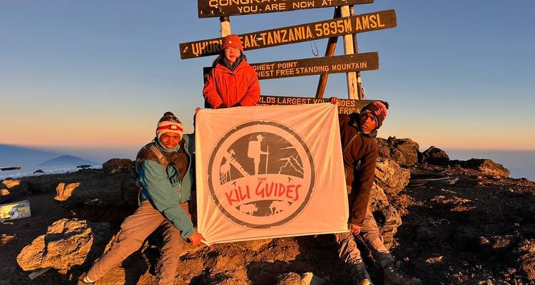 Groupe de grimpeurs au sommet d'une montagne avec un panneau
