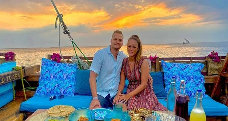 Paar sitzt auf einem Boot mit Sonnenuntergang im Hintergrund.