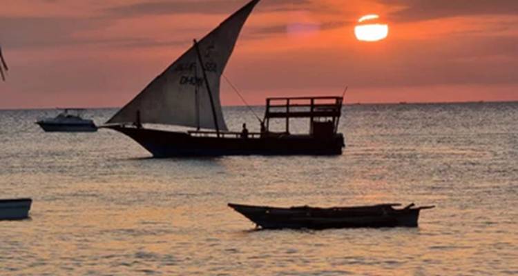 Traditionelles Segelboot bei Sonnenuntergang über dem Ozean.