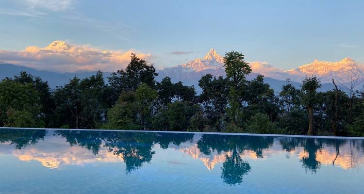 Montagnes se reflétant dans une piscine à débordement au lever du soleil.