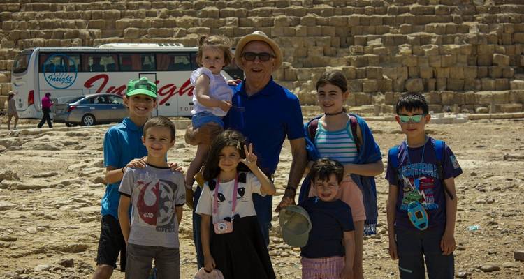 Een familiegroep die poseert voor oude stenen en een tourbus.