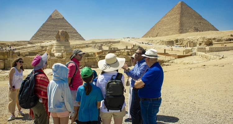 Toeristen die piramides en een sfinx in een woestijn observeren.