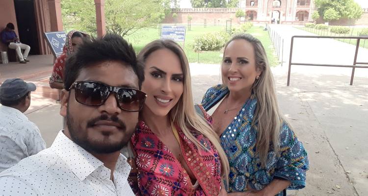 Drie mensen poseren bij een historische plek.