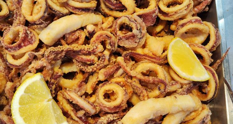 Gros plan d'anneaux de calamars frits avec des quartiers de citron.