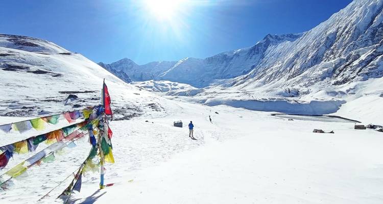Uitgestrekt besneeuwd landschap met bergen en kleurrijke gebedsvlaggen.