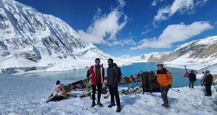 Groep mensen die poseren in besneeuwde berglandschap met vlaggen.