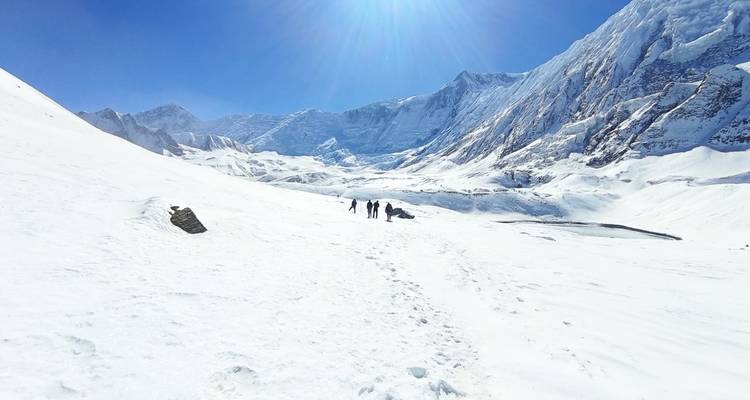 Sneeuwbedekt berglandschap met heldere lucht en figuren in de verte.