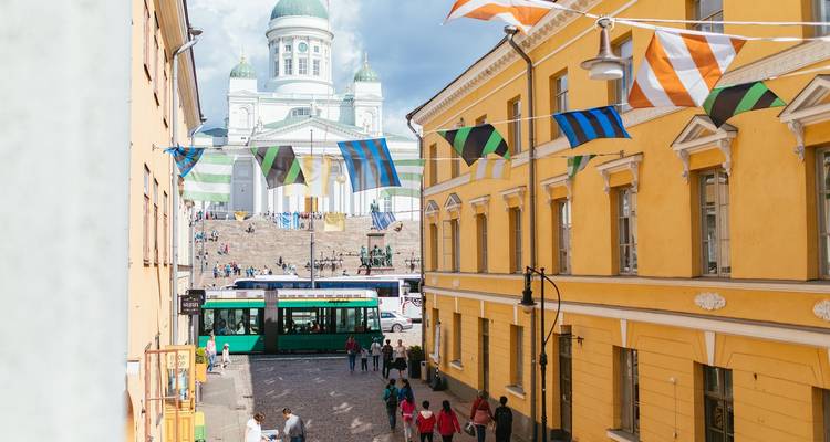 Straatbeeld met tram, wandelende mensen en een historische kerk op de achtergrond.
