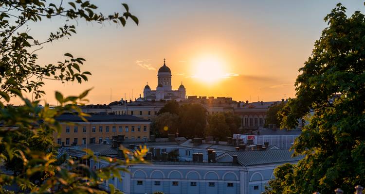Zonsondergang over een stadsgezicht met een prominent koepelgebouw.