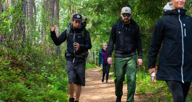 Groep mensen die langs een bospad wandelen.