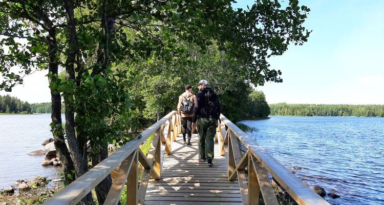 Mensen die over een houten brug lopen met uitzicht op een meer.