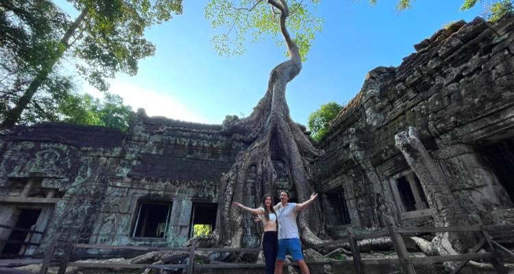 Couple posing in front of tree roots engulfing a temple.