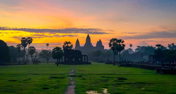 Angkor Wat silhouette at dawn with colorful sky.