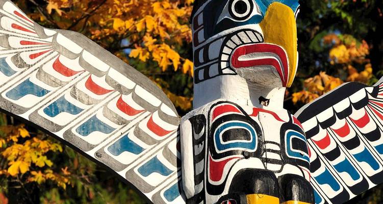 Aigle totem sculpté coloré aux ailes déployées contre les feuilles d'automne dans le parc Stanley de Vancouver