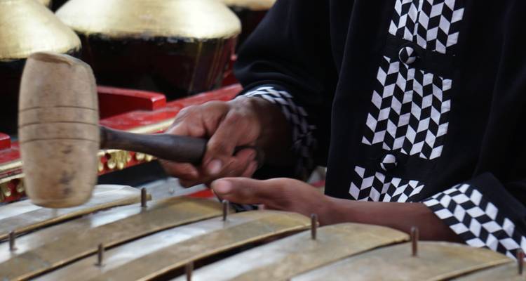 Close-up of hands playing a traditional Balinese instrument.