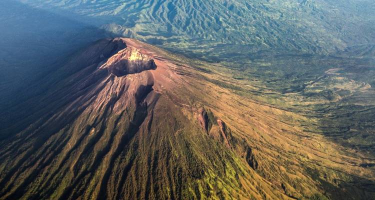 Aerial view of a volcanic mountain with lush green slopes.
