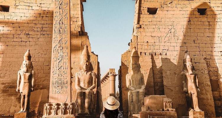 Ruines de l'Égypte ancienne avec une personne regardant des statues.