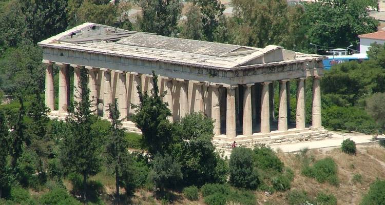 Ancient temple with tall columns and greenery around.