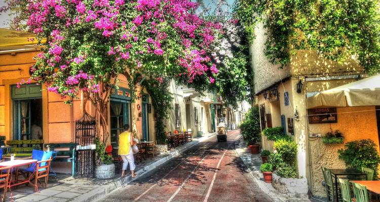Charming street with colorful flowers and buildings, person walking.