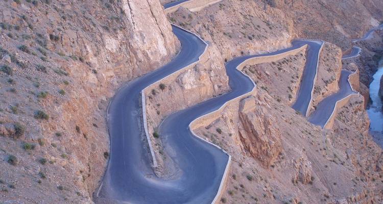 Kurvenreiche Bergstraße, die sich durch eine felsige Landschaft schlängelt.