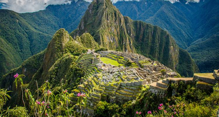Ikonische Inka-Zitadelle von Machu Picchu, gelegen auf einem üppigen Bergkamm mit imposanten grünen Bergen rundherum