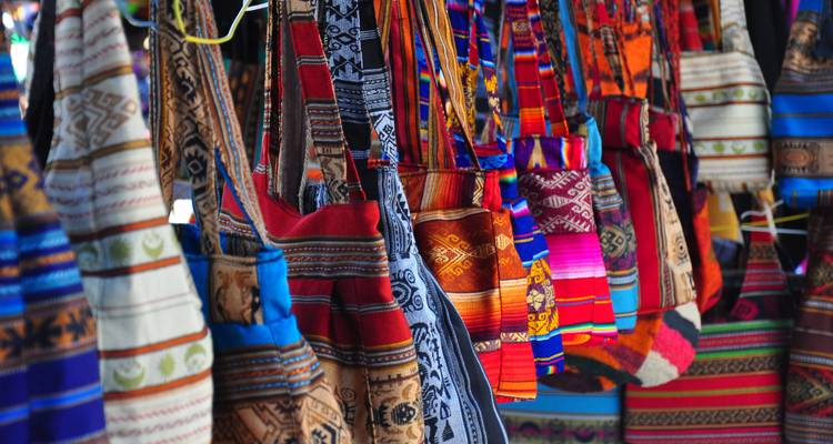 Leuchtend farbige geflochtene Taschen hängen in Reihen an einem Marktstand des indigenen Volkes.