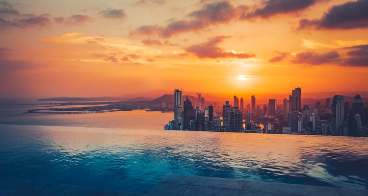 Coucher de soleil dramatique sur la skyline de la Ville de Panama vu au-delà d'une piscine à débordement donnant sur la baie.