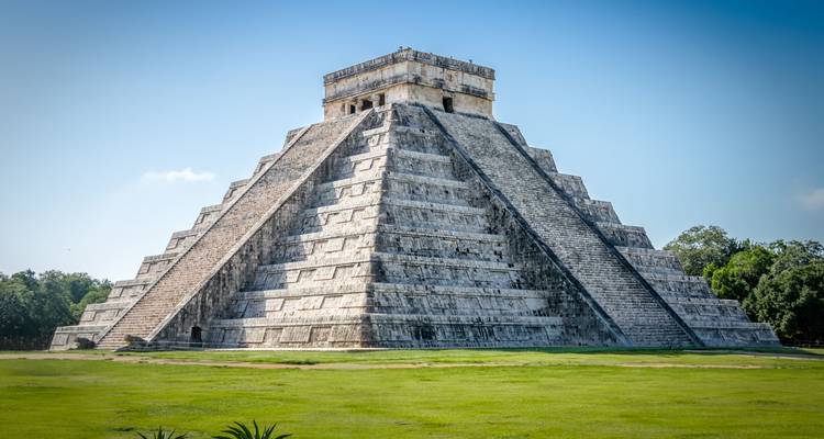 La Pirámide de Kukulkán se eleva desde unos céspedes verdes bien cuidados bajo un cielo azul y despejado de Yucatán.