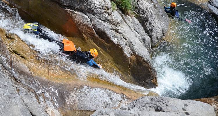 Menschen, die eine felsige Böschung hinunter ins Wasser rutschen.