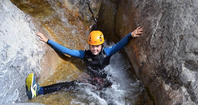 Person genießt Canyoning zwischen Felsen und Wasser.