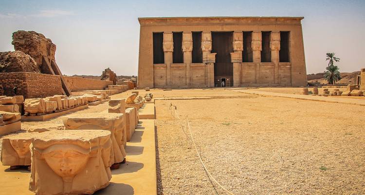 Zandstenen gevel van de Tempel van Hathor in Dendera met omgevallen kapitelen die langs de binnenplaats zijn opgesteld