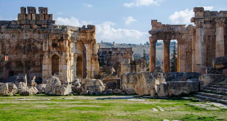 Ruines antiques avec des colonnes de pierre sous un ciel nuageux.