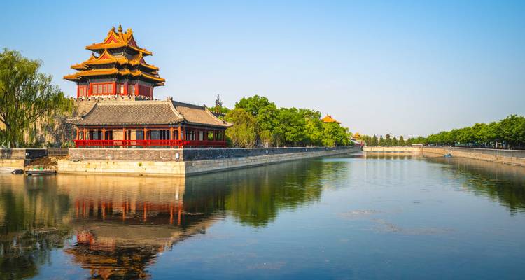 Torre de la esquina de la Ciudad Prohibida de Beijing reflejada en el foso bajo la luz clara de la mañana
