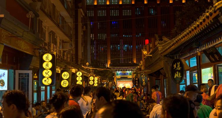 Animada calle del mercado nocturno en Xi'an llena de letreros de neón y puestos de comida