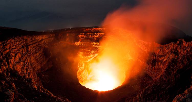 Glowing lava crater of Masaya Volcano emitting orange smoke at night.