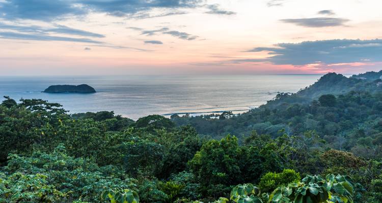Rustig uitzicht op het regenwoud aan de kust bij zonsondergang met uitzicht op de Grote Oceaan en een klein eilandje voor de kust in Costa Rica