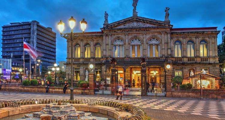 Het verlichte Nationaal Theater van Costa Rica in San José tijdens het schemeren met fontein en vlag op de voorgrond