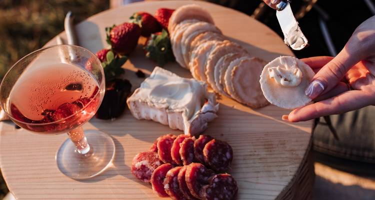 Kaas, salami, aardbeien en een drankje op een houten plank.
