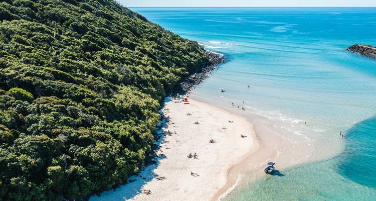 Vista aérea de una pequeña playa con aguas azules cristalinas.