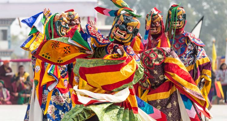 Group of performers in traditional Bhutanese masks and costumes.