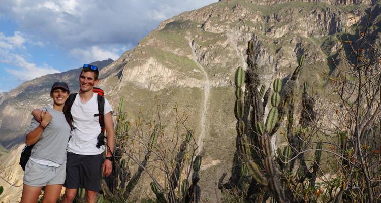 Pareja caminando por un paisaje desértico montañoso.