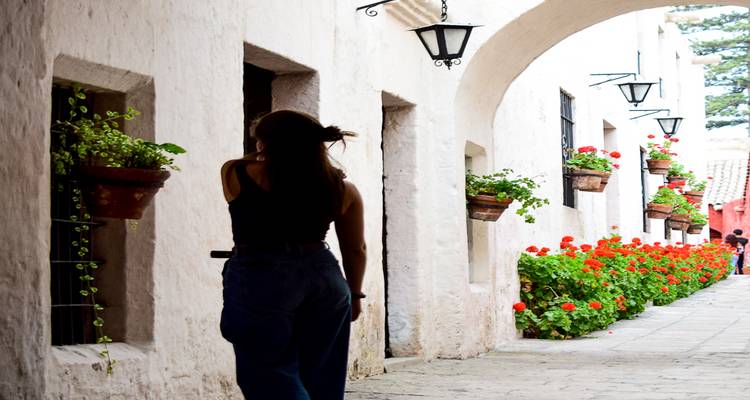 Mujer caminando por una calle encantadora bordeada de flores.