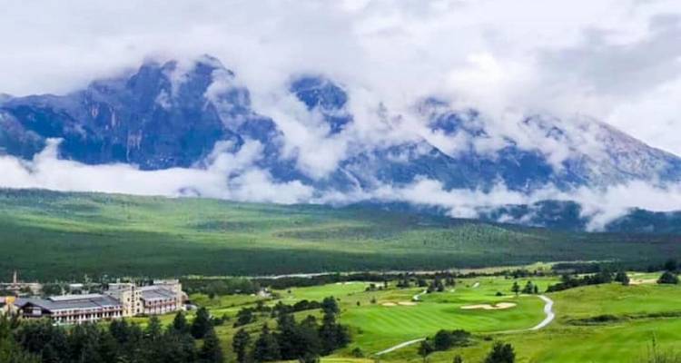 Golfbaan met bergen gehuld in mist en wolken.