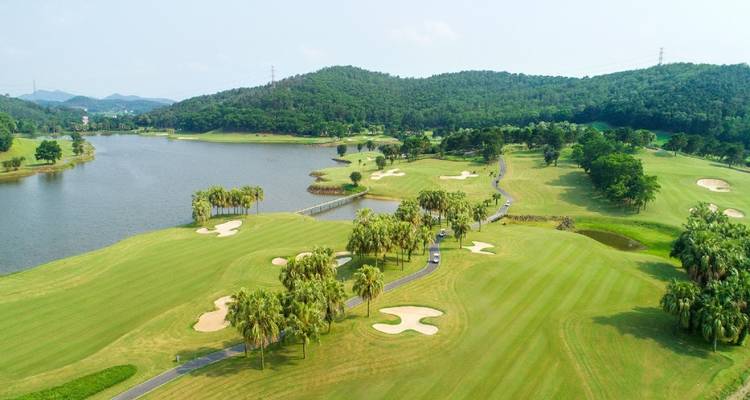 Uitgestrekt golfterrein met meren en glooiende heuvels.